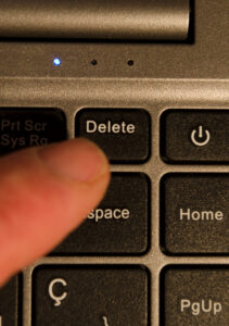 pressing delete key on laptop. finger pressing delete key. laptop keyboard with close-up on delete key
