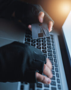 Shot of an unrecognisable hacker using a laptop to hack into a credit account.