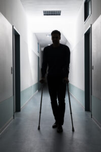 Silhouette Of Disabled Man Walking With Crutches In Hospital